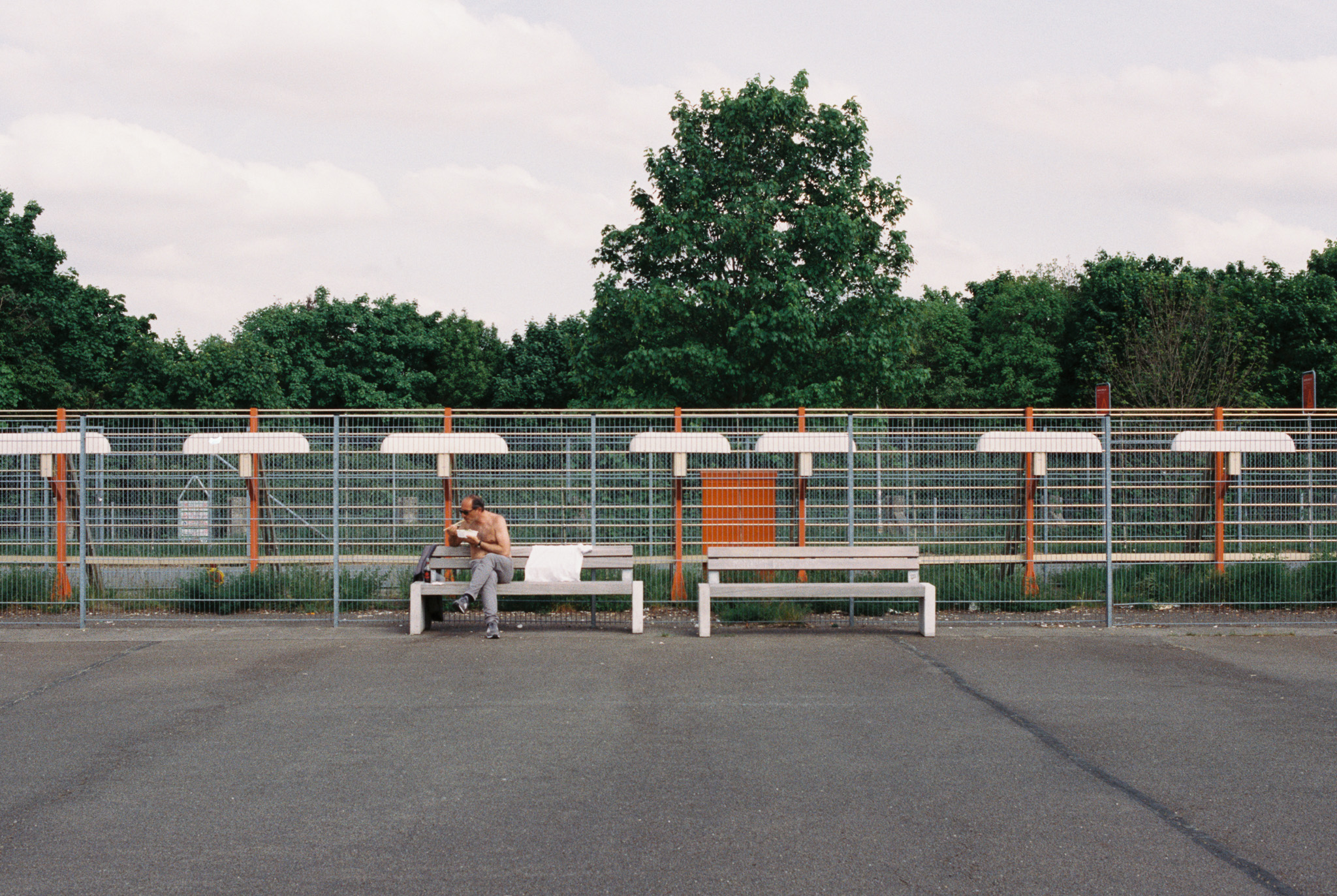Person sitting alone on a bench in front of metal construction fencing