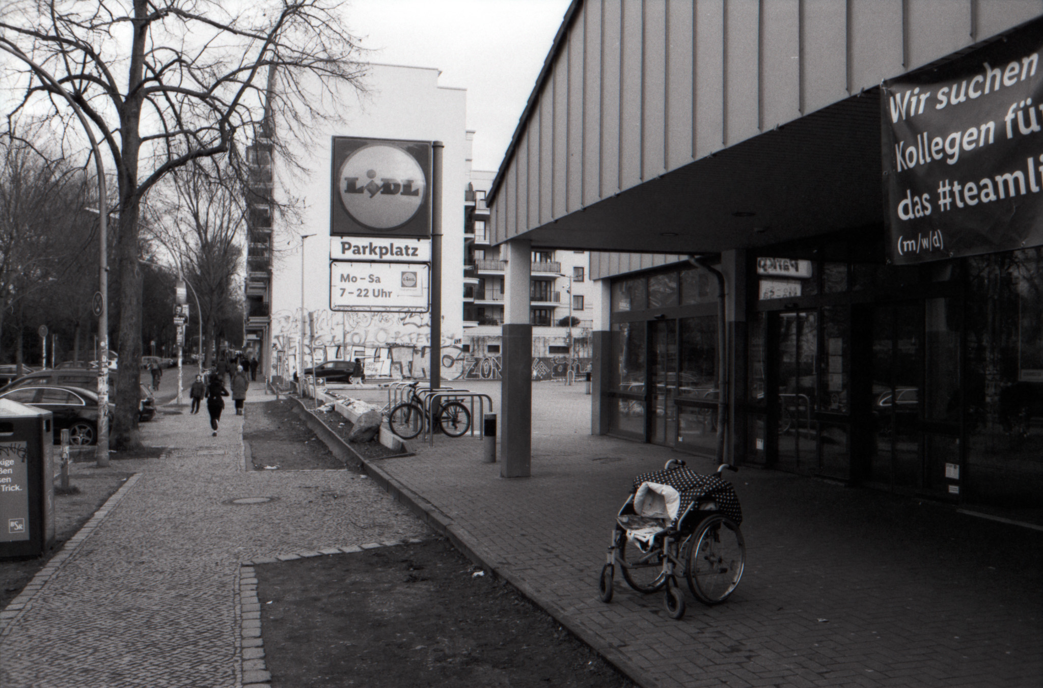 Wheelchair parked outside a Lidl supermarket on a Berlin sidewalk, black and white