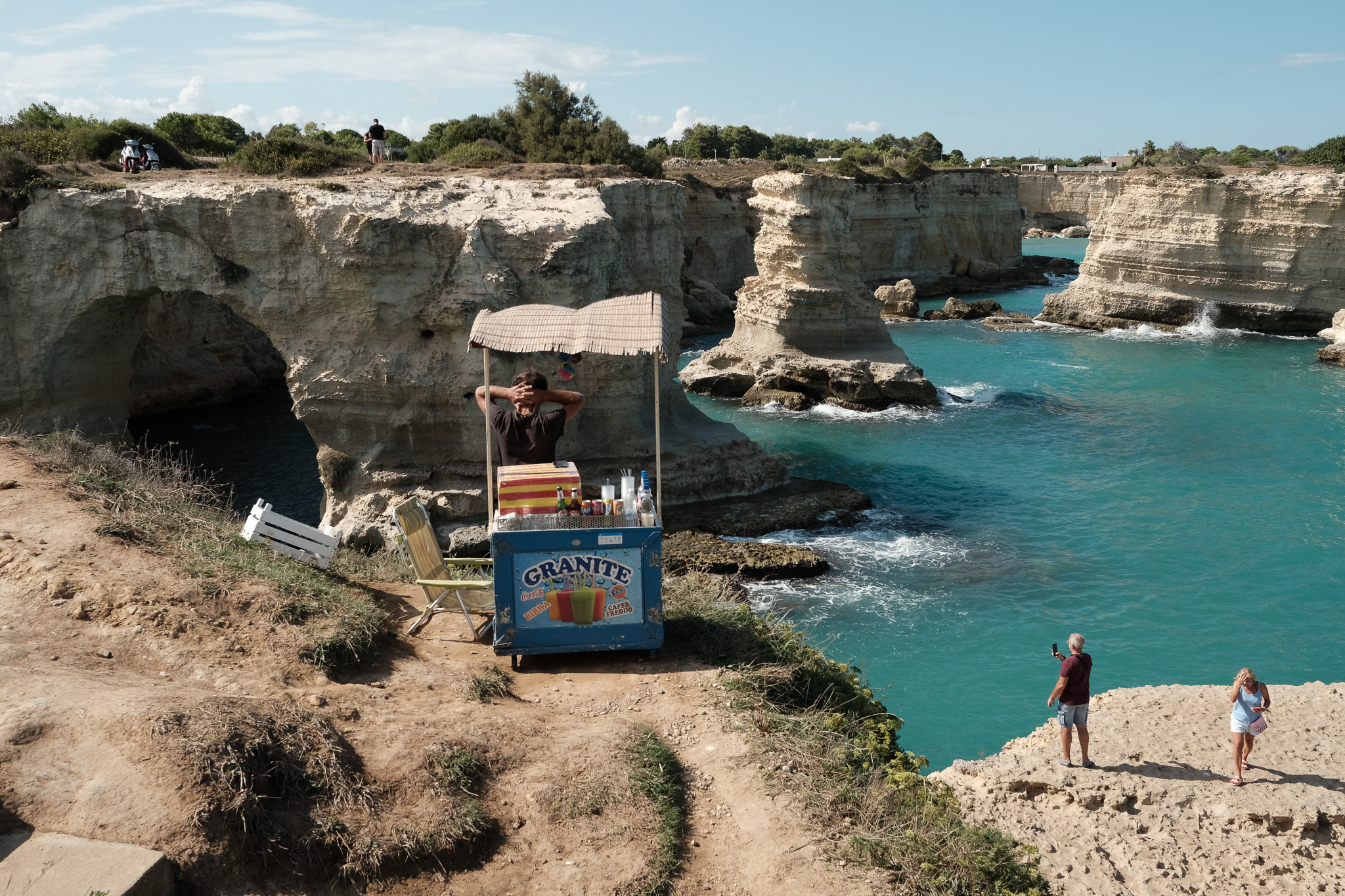 Granita stand perched on limestone cliffs above turquoise sea, Puglia