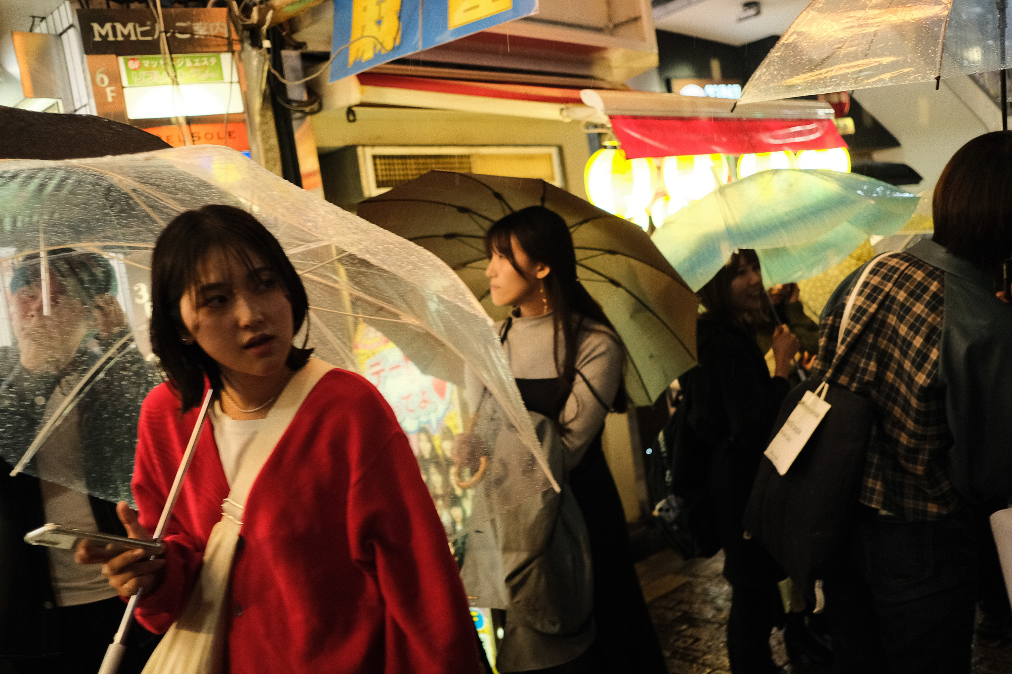 People with transparent umbrellas walking in the rain at night, Tokyo