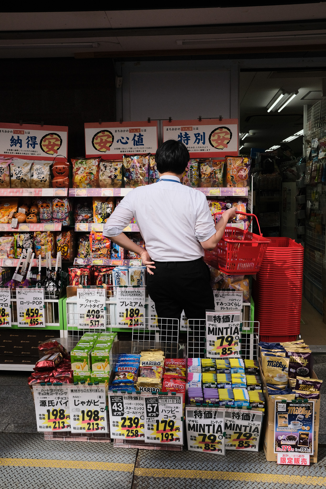 Man shopping at a brightly lit convenience store entrance at night, Japan